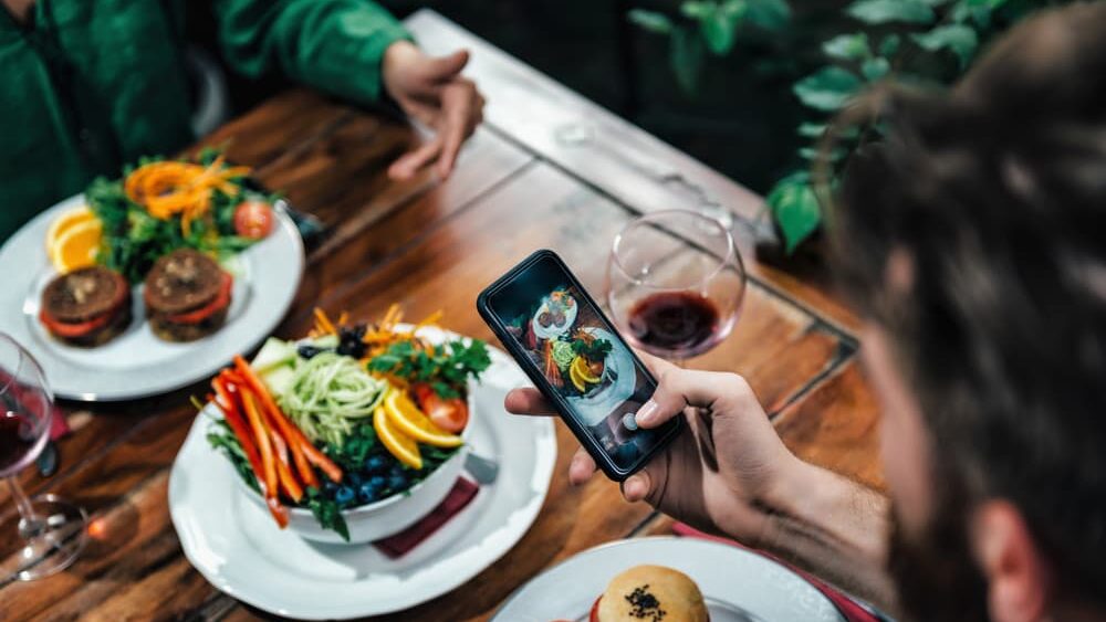 Guests dining at The Point Restaurant taking a photo of the vegan dishes with an iPhone before eating their meals